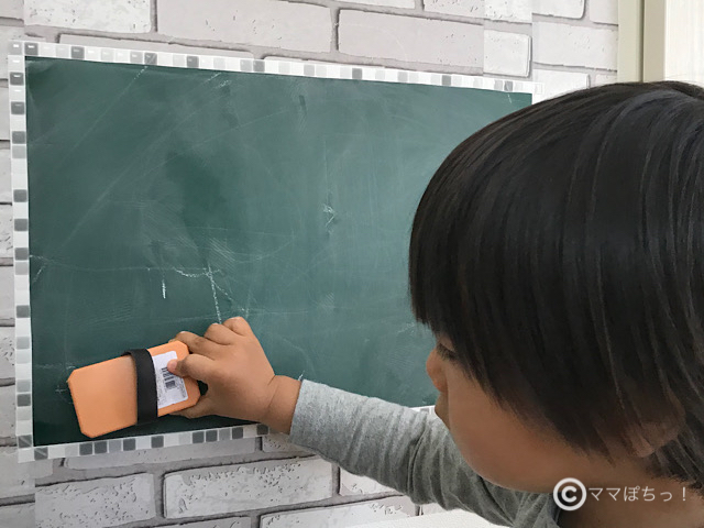 セリアの黒板シートの落書き(チョーク)を、黒板消しで消す子供の写真です。