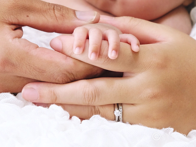 赤ちゃんの小さい手を包む親の手の写真です。